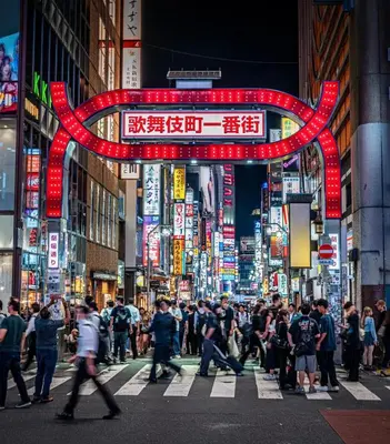 a crowd of people crossing a busy city street at night at \u65b0\u5bbf\u5e02\u4e2d\u5fc3\u7d27\u90bb\u6b4c\u821e\u4f0e\u753a\u65b0\u5bbf\u30b4\u30fc\u30eb\u30c7\u30f3\u885713 in Tokyo