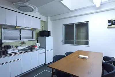 a kitchen with white cabinets and a wooden table at HOSTEL EstLiLas KANDA \u30a2\u30cd\u30c3\u30af\u30b9 in Tokyo