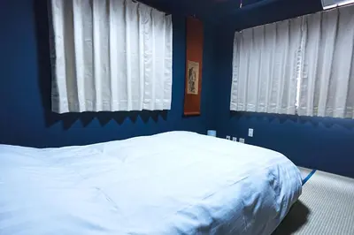 a blue bedroom with a white bed with two windows at HOSTEL EstLiLas KANDA \u30a2\u30cd\u30c3\u30af\u30b9 in Tokyo