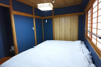a bedroom with a white bed and a wooden door at HOSTEL EstLiLas KANDA \u30a2\u30cd\u30c3\u30af\u30b9 in Tokyo