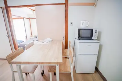 a kitchen with a table and a microwave and a refrigerator at 302Room 1 Stop from Ikebukuro Entire 33m on 3st Floor 2 Bedrooms for up to 6 Guests 3Minute Walk to Don Quijote in Tokyo