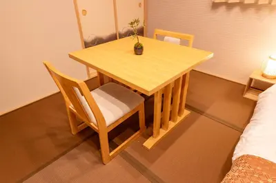 a wooden table and chair with a plant on it at HOTEL NESTA OSHIAGE Two in Tokyo