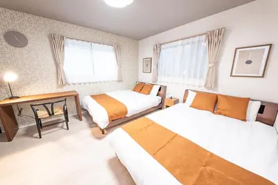 a bedroom with two beds and a desk in it at HOTEL NESTA OSHIAGE Two in Tokyo