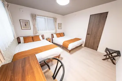 a bedroom with two beds and a table in it at HOTEL NESTA OSHIAGE Two in Tokyo