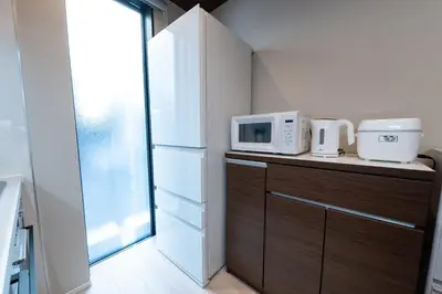 a kitchen with a refrigerator and a microwave on a counter at HOTEL NESTA OSHIAGE Two in Tokyo