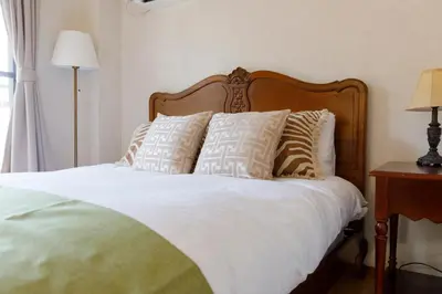 a bedroom with a bed with white sheets and pillows at New - 4 min to Shinjuku! 4 Bedrooms Villa 970 sq ft in Koenji, 10 people, 8 min walk to JR Koenji station - GRADIA Koenji Hotel in Tokyo