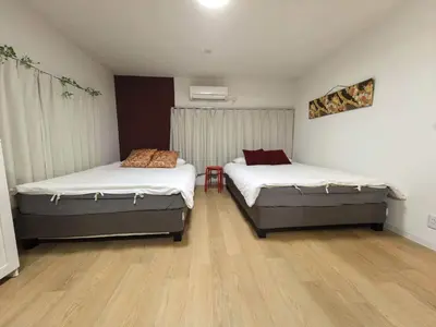 two beds in a room with wooden floors at AYA House in Tokyo