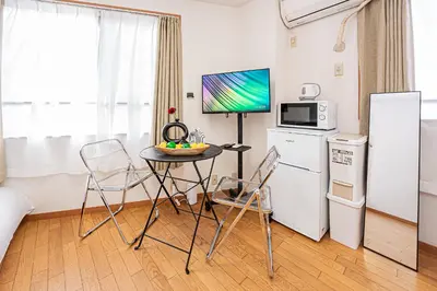 a kitchen with a table and a refrigerator and a table and chairs at Mi-APT Honkomagome in Tokyo