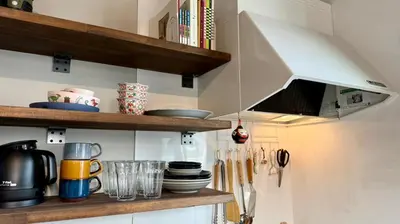 a kitchen with a shelf with dishes and utensils at SW House in Tokyo