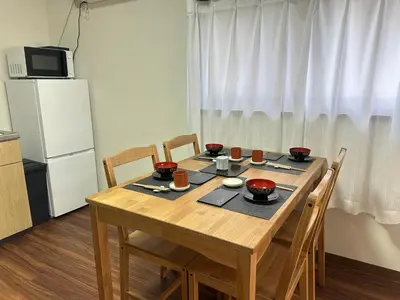 a kitchen with a wooden table with chairs and a refrigerator at Akihabara, Skytree, Disney, Asakusa Temple, Traditional Japanese Ryokan, Airport Pick-up and Drop-off in Tokyo
