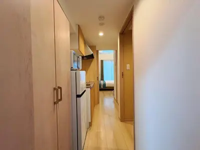 a hallway leading to a kitchen with a refrigerator at \u738b\u5b50Stay\u4f73 in Tokyo