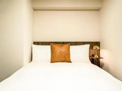 a bedroom with a white bed with a brown pillow at Section L Akihabara in Tokyo