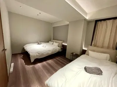 two beds in a small room with white sheets at \u4f4d\u4e8e\u4e1c\u4eac\u6c5f\u6237\u5ddd\u533a\u4e1c\u5c0f\u5ca9\u662f\u9002\u5408\u5bb6\u5ead\u4e0e\u670b\u53cb\u56e2\u4f53\u5165\u4f4f\u7684\u6574\u5957\u65e5\u5f0f\u6c11\u5bbf in Tokyo