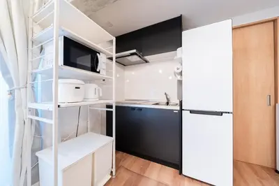 a kitchen with a white refrigerator and a sink at Jeminith Ikebukuro Tokyo in Tokyo