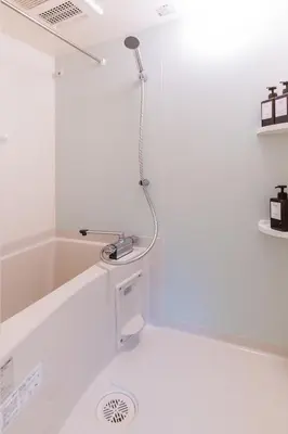 a shower in a white bathroom with a sink at Grado Horikiri in Tokyo