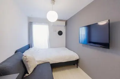 a small room with a bed and a flat screen tv at Grado Horikiri in Tokyo