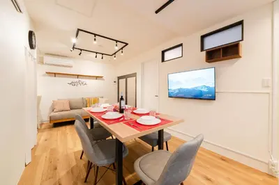 a dining room and living room with a table and chairs at Yuka House Komagome 1\u968e \u81ea\u8ee2\u8eca\u4ed8 \u304a\u3082\u3061\u3083\u3068\u843d\u66f8\u304d\u58c1\u306e\u30d7\u30ec\u30a4\u30eb\u30fc\u30e0 \u5bb6\u65cf\u5411\u3051 in Tokyo