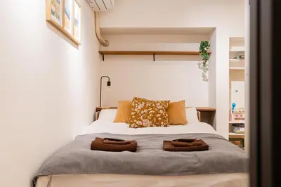 a bedroom with a bed with two towels on it at Yuka House Komagome 1\u968e \u81ea\u8ee2\u8eca\u4ed8 \u304a\u3082\u3061\u3083\u3068\u843d\u66f8\u304d\u58c1\u306e\u30d7\u30ec\u30a4\u30eb\u30fc\u30e0 \u5bb6\u65cf\u5411\u3051 in Tokyo