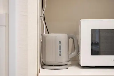 a coffee cup is sitting next to a microwave at Yuka House Komagome 1\u968e \u81ea\u8ee2\u8eca\u4ed8 \u304a\u3082\u3061\u3083\u3068\u843d\u66f8\u304d\u58c1\u306e\u30d7\u30ec\u30a4\u30eb\u30fc\u30e0 \u5bb6\u65cf\u5411\u3051 in Tokyo