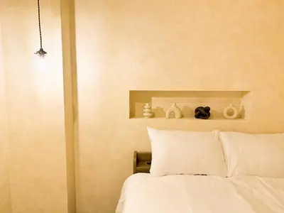 a bedroom with a bed with white sheets and vases at 52 House Shimbashi in Tokyo