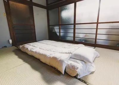 a bed with white sheets in a room with a window at \u30a2\u30fc\u30d0\u30f3\u30b8\u30e3\u30f3\u30b0\u30eb in Tokyo