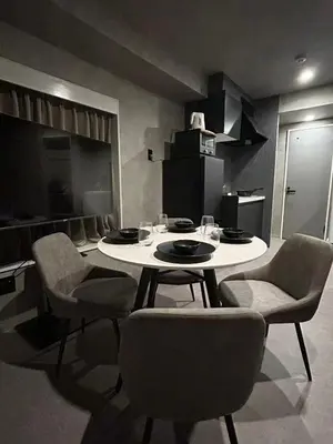 a dining room with a table and chairs and a kitchen at Domo Stay in Tokyo