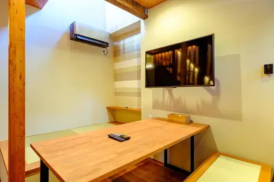 a room with a table and a tv on a wall at Yolo Asakusa Stay in Tokyo