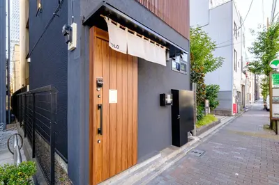 a building with a wooden door on the side of a street at Yolo Asakusa Stay in Tokyo