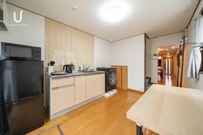 a kitchen with a refrigerator and a table in it at unito villa SHINJUKU in Tokyo