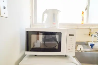 a white microwave sitting on top of a kitchen counter at 403Room 1 Stop from Ikebukuro Entire 35m on 4st Floor 2 Bedrooms for up to 6 Guests 3Minute Walk to Don Quijote in Tokyo