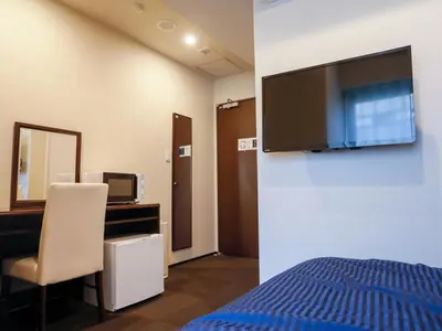 a bedroom with a bed and a tv on a wall at HOTEL LiVEMAX Higashi Ginza in Tokyo