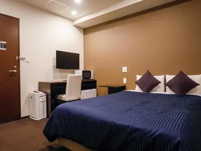 a bedroom with a bed and a desk with a computer at HOTEL LiVEMAX Higashi Ginza in Tokyo
