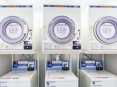 a row of washers and dryers in a laundry room at HOTEL LiVEMAX Higashi Ginza in Tokyo