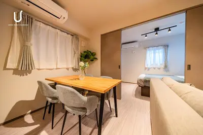 a room with a table and chairs and a bed at unito residence SHINJUKU Wakamatsu in Tokyo