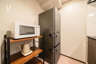 a kitchen with a microwave and a refrigerator at unito residence SHINJUKU Wakamatsu in Tokyo