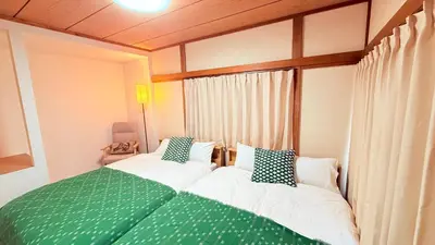 a bedroom with two beds with green and white pillows at Higashi-Jujo-house \u7950\u6cfd KI0478 in Tokyo