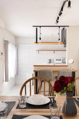 a dining room with a table with a vase of roses at Yuka House Komagome 2\u968e \u81ea\u8ee2\u8eca\u4ed8 \u304a\u3082\u3061\u3083\u3068\u843d\u66f8\u304d\u58c1\u306e\u30d7\u30ec\u30a4\u30eb\u30fc\u30e0 \u5bb6\u65cf\u5411\u3051 in Tokyo