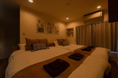 a bedroom with two large beds with towels on them at Yuka House Komagome 2\u968e \u81ea\u8ee2\u8eca\u4ed8 \u304a\u3082\u3061\u3083\u3068\u843d\u66f8\u304d\u58c1\u306e\u30d7\u30ec\u30a4\u30eb\u30fc\u30e0 \u5bb6\u65cf\u5411\u3051 in Tokyo