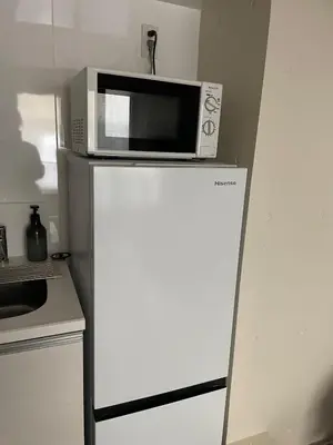 a microwave on top of a refrigerator in a kitchen at Tkm\u767d\u91d15\u4e01\u76ee in Tokyo