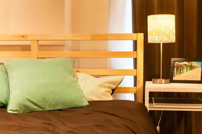 a bed with a green pillow next to a lamp at Imb\u753a\u5c4b4\u4e01\u76ee302 in Tokyo