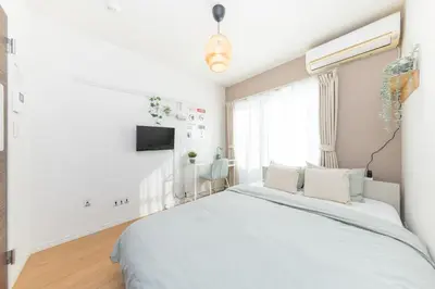 a white bedroom with a bed and a tv at The House IKEBUKURO 301 in Tokyo