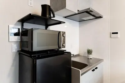 a microwave on top of a refrigerator in a kitchen at Casa-T\u4e94\u53cd\u91ce in Tokyo