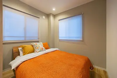 an orange bed in a room with two windows at Lino Stay Kasai 'elua in Tokyo