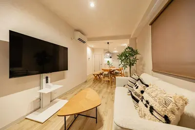 a living room with a couch and a tv on a wall at Lino Stay Kasai 'ekol in Tokyo