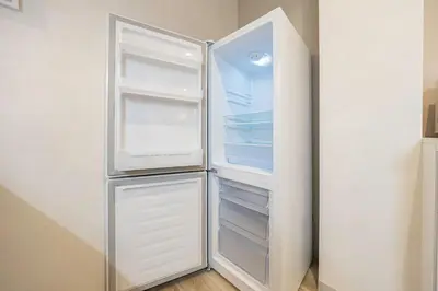 an empty refrigerator with its door open in a kitchen at Lino Stay Kasai 'ekol in Tokyo