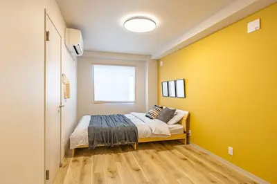 a bedroom with a bed and a yellow wall at Lino Stay Kasai 'ekol in Tokyo