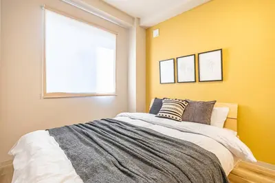 a bedroom with a bed with yellow walls and a window at Lino Stay Kasai 'ekol in Tokyo