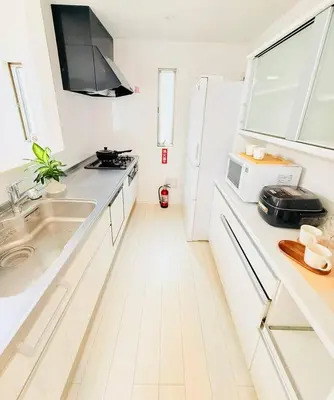 a white kitchen with a sink and a microwave at Higashijūjō, Kita City house KI0321 in Tokyo