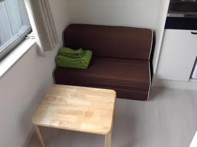 a small room with a couch and a wooden stool at Shitamachi Base in Tokyo