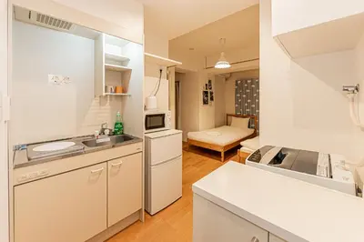 a kitchen with white cabinets and a couch in a room at 67 Apartment Hotel Asakusa in Tokyo